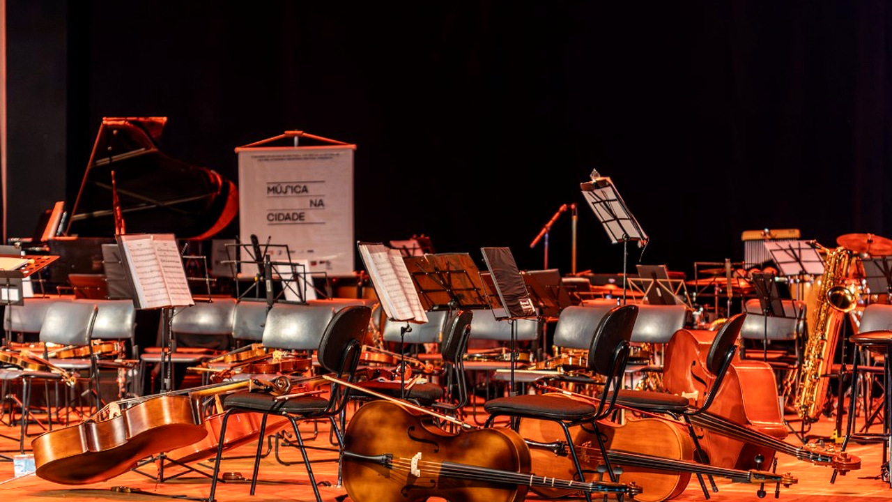 Palco preparado com violoncelos e partituras
