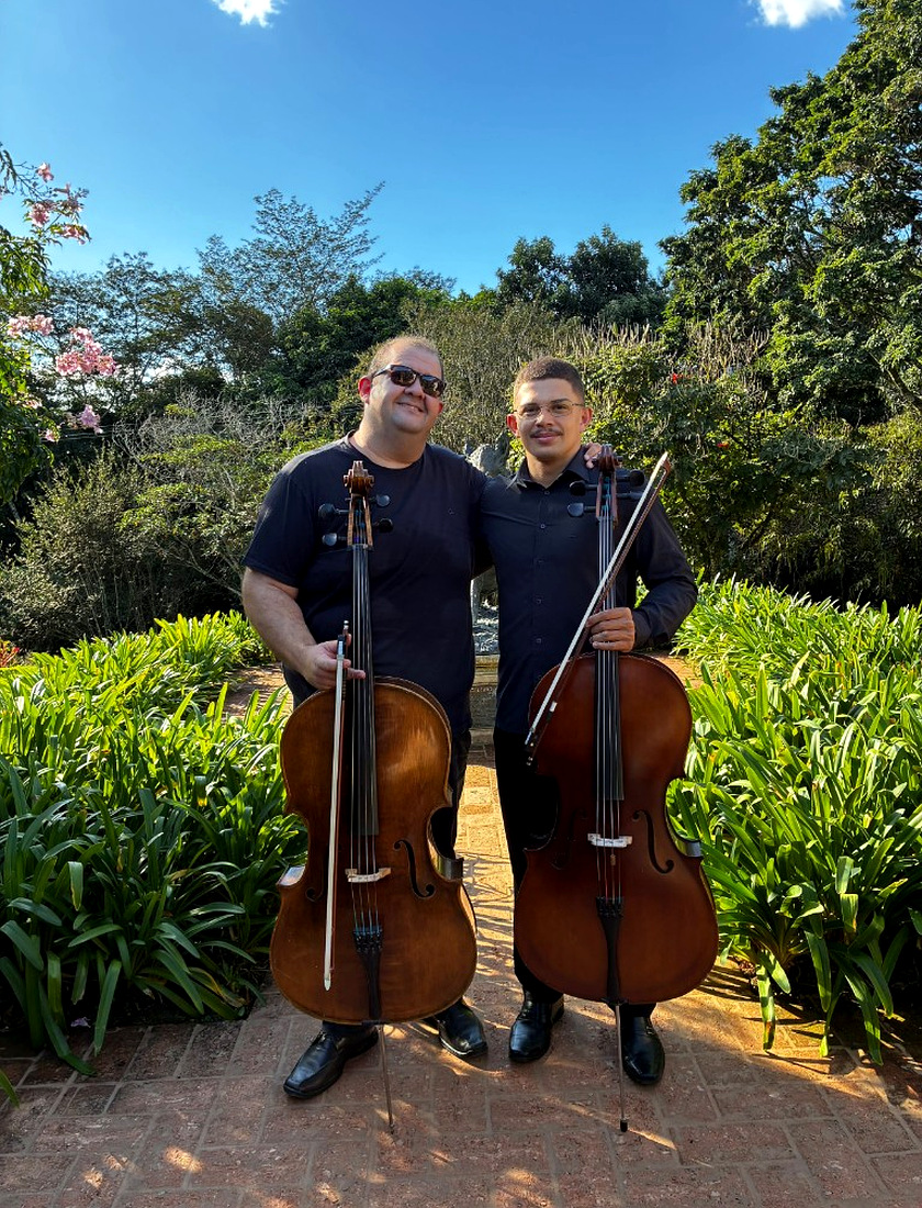 Giovanni e colega com violoncelos no jardim